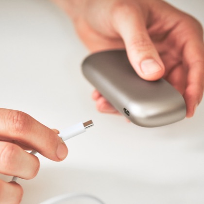 Person inserting USB Charging Cable into IQOS Originals Holder